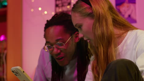 two friends laughing while looking at a phone