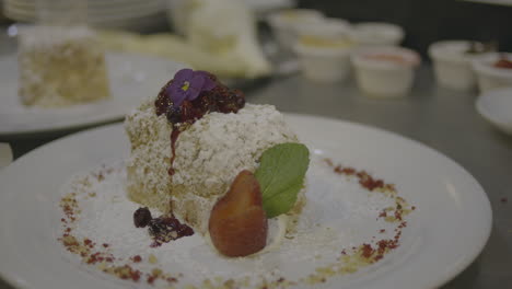 una vista cercana del chef coloca una flor en la parte superior de un delicioso postre gourmet adornado con bayas vibrantes