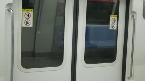 an interior selected focus view at window on subway's door, view of the doors on a commuter subway car while train is moving