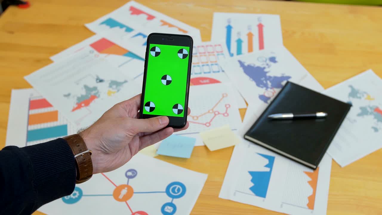 hombre usando teléfono inteligente con pantalla verde en el escritorio de la oficina, espacio de trabajo, buscar información