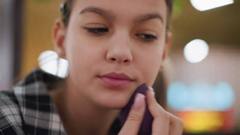 hermosa dama ajustando cuidadosamente el maquillaje con esponja de belleza, asegurando una aplicación suave y uniforme, expresión enfocada destaca el cuidado de sí mismo, rutina de belleza y mejora impecable de la complexión