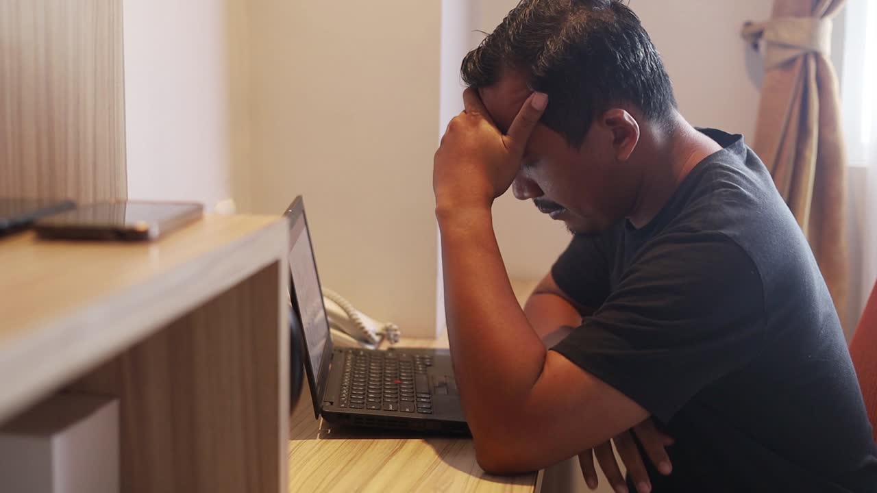 Portrait of Sad asian man working using laptop in hotel room