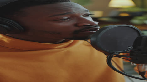hombre con auriculares hablando en un micrófono profesional en un estudio de grabación