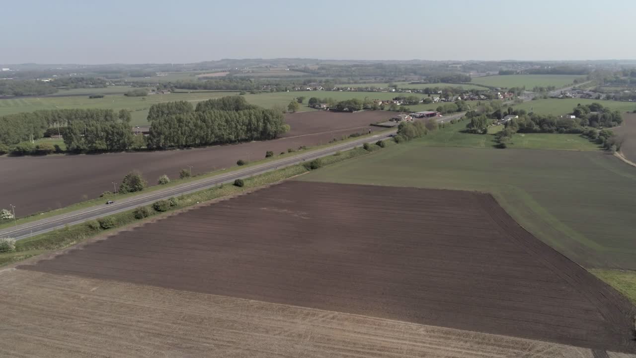 Drone aerial slow rising view above British A580 East Lancs highway in rural agricultural countryside