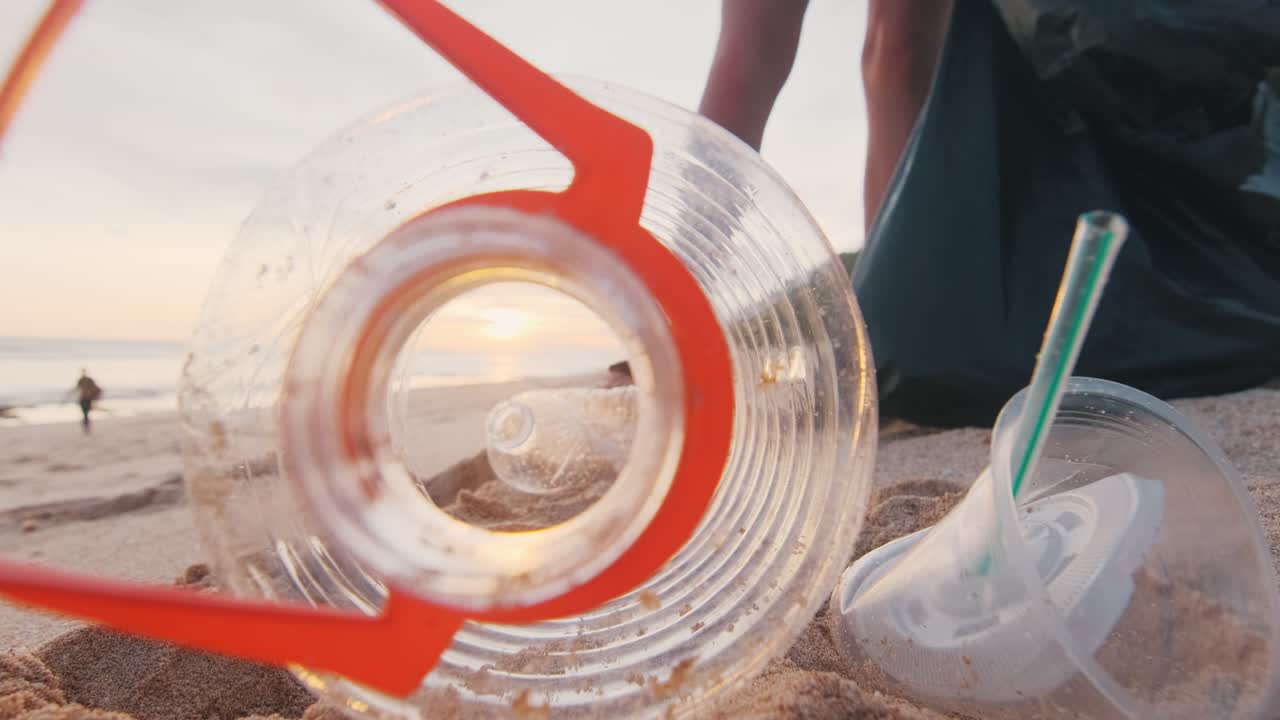 생태운동가들이 해변에서 쓰레기를 모으고 플라스틱 병을 가방에 넣고 떠난다.