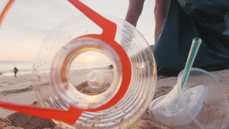 ecoactivista recogiendo basura de la playa y botellas de plástico en bolsas y saliendo