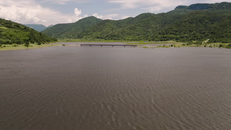 Plätschernde-Oberfläche-Des-Großen-Tkibuli-Wasserreservoirs-Mit-Dahinterliegender-Brücke