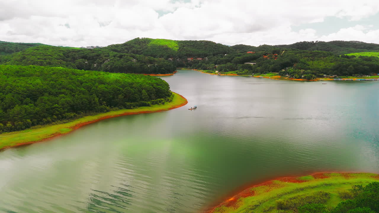 se eleva por encima de un paisaje montañoso impresionante mientras un barco de pesca solitario se desliza a través de las aguas tranquilas de un lago prístino.