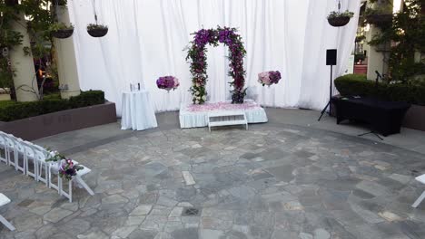 drone backward movement view of a empty wedding stage, wedding ceremony under the open sky and a fountain at the center of the hall