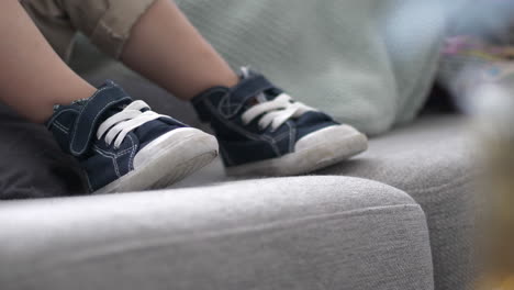 adorable small casual shoes on children feet while sitting on couch