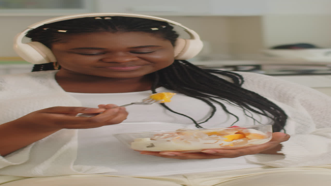 Woman with headphones eating fruit salad