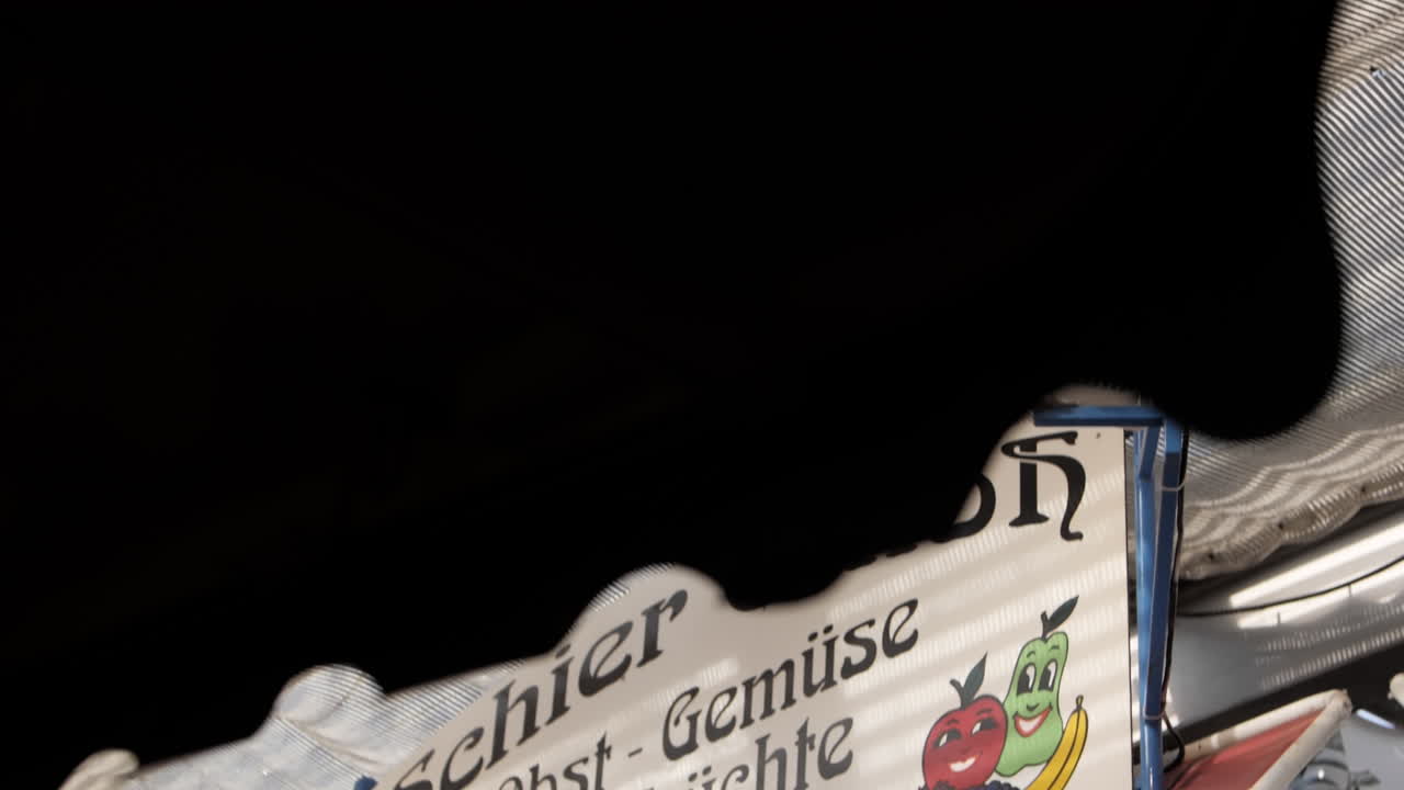 카를스플라츠 (carlsplatz) 의 고해상도 영상으로 글과 그림으로 된 과일과 채소와 얼굴이 있는 색 표지판이 그려져 있습니다.