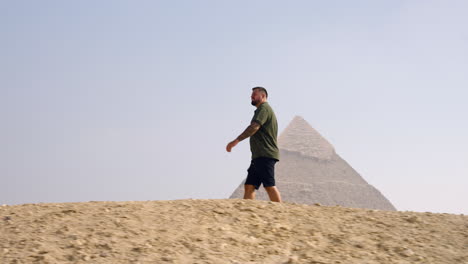 siguiendo a un hombre caminando cerca de la pirámide de la meseta de giza cerca de el cairo, egipto.