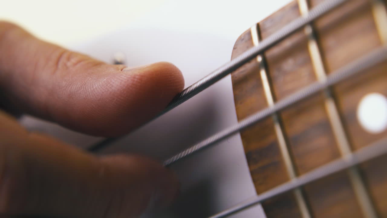 person tries backbeat technique on white bass guitar closeup
