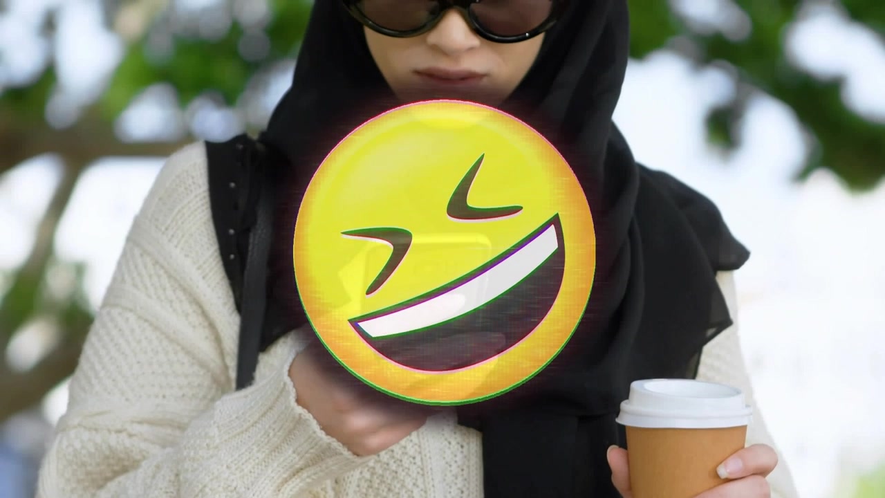 Animazione di un'emoji sorridente su una donna musulmana che usa lo smartphone.