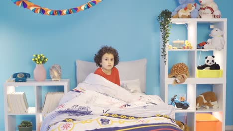 a boy having a nightmare wakes up from the bed in fear.