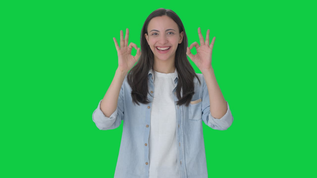 Ragazza indiana felice che mostra il segno dell'ok Green screen