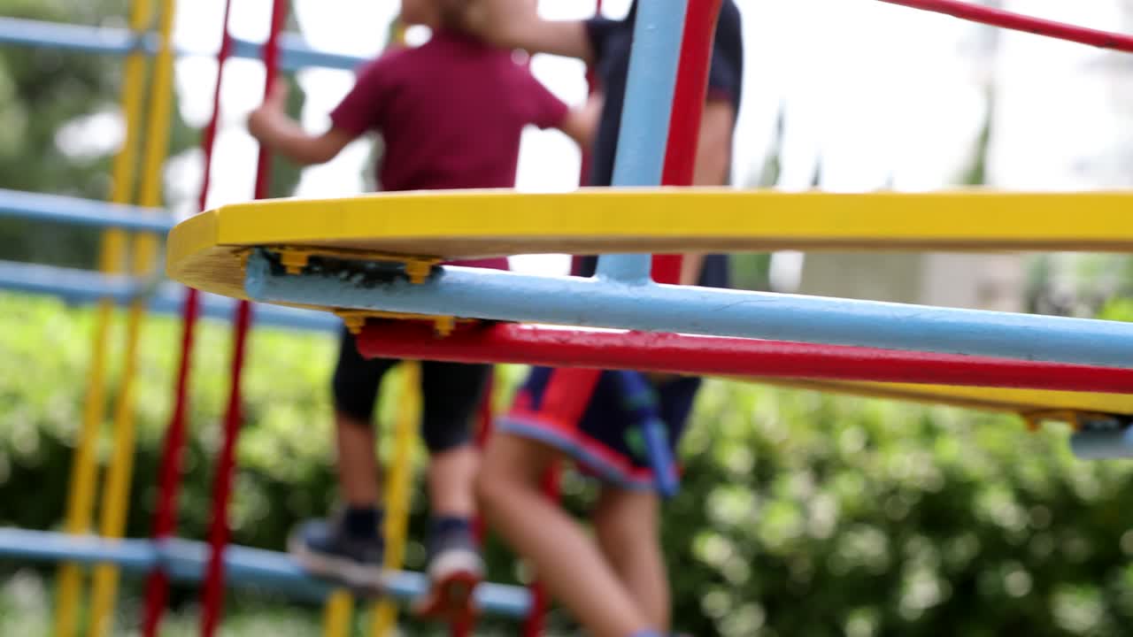Carrusel de parque infantil girando con niños de fondo trepando en la barra de monos.