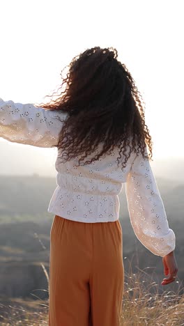 woman with curly hair posing in golden hour sunlight outdoors