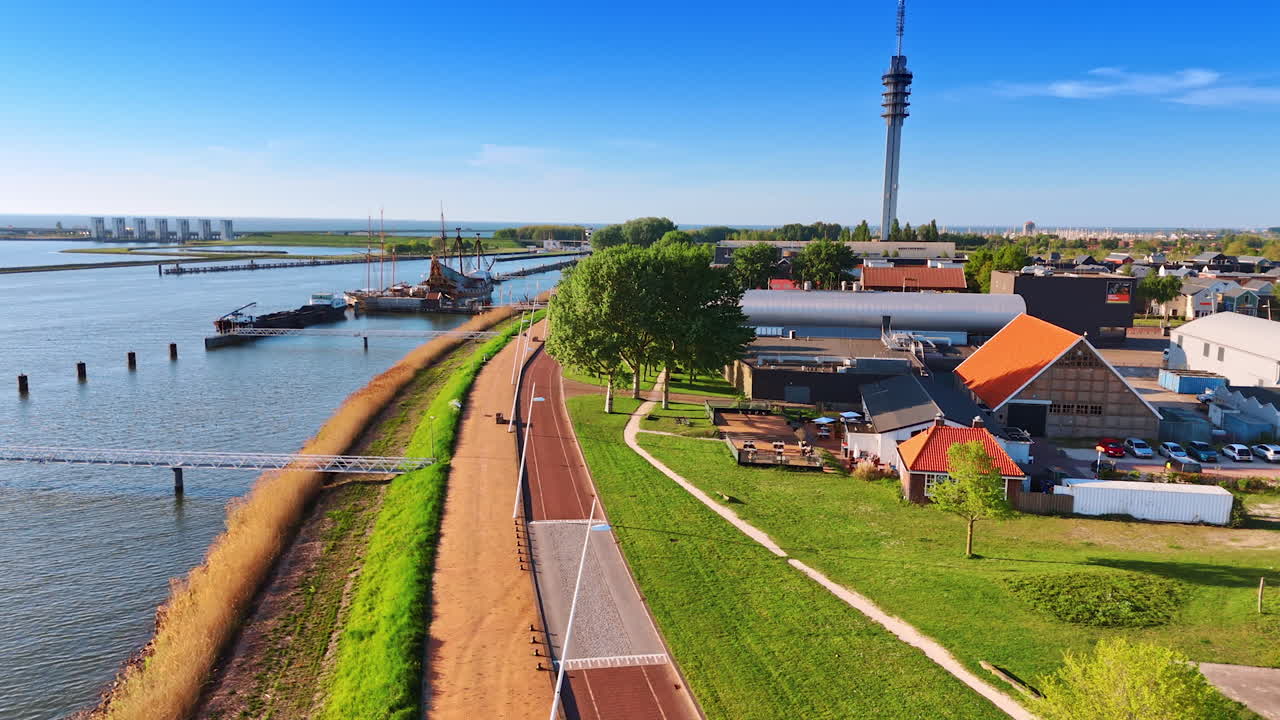 Waterfront with the bridges to the boats. Drone footage over the shore in Lelystad, the Netherlands. Approaching telecom tower and Museum Batavialand.