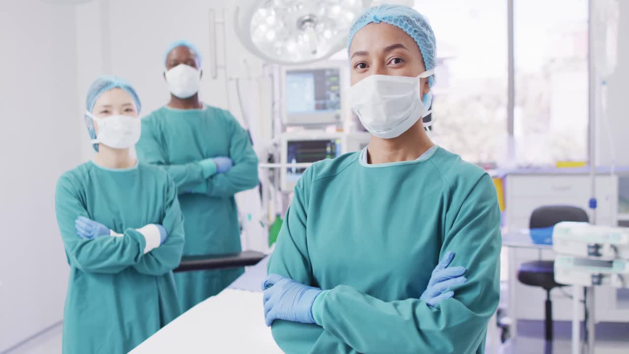 video de tres cirujanos diversos vestidos para la operación en el quirófano