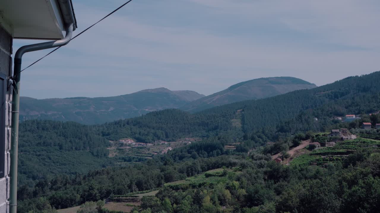 vista serena de montañas verdes y colinas capturadas desde el lado de una casa en un día despejado