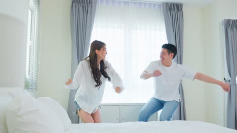 happy couple dancing on bed