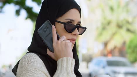 Frau-Im-Hijab-Spricht-Mit-Dem-Handy,-Während-Sie-Kaffee-4k-Trinkt