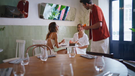 cafe waiter serving couple women dinner. happy smiling besties feeling carefree