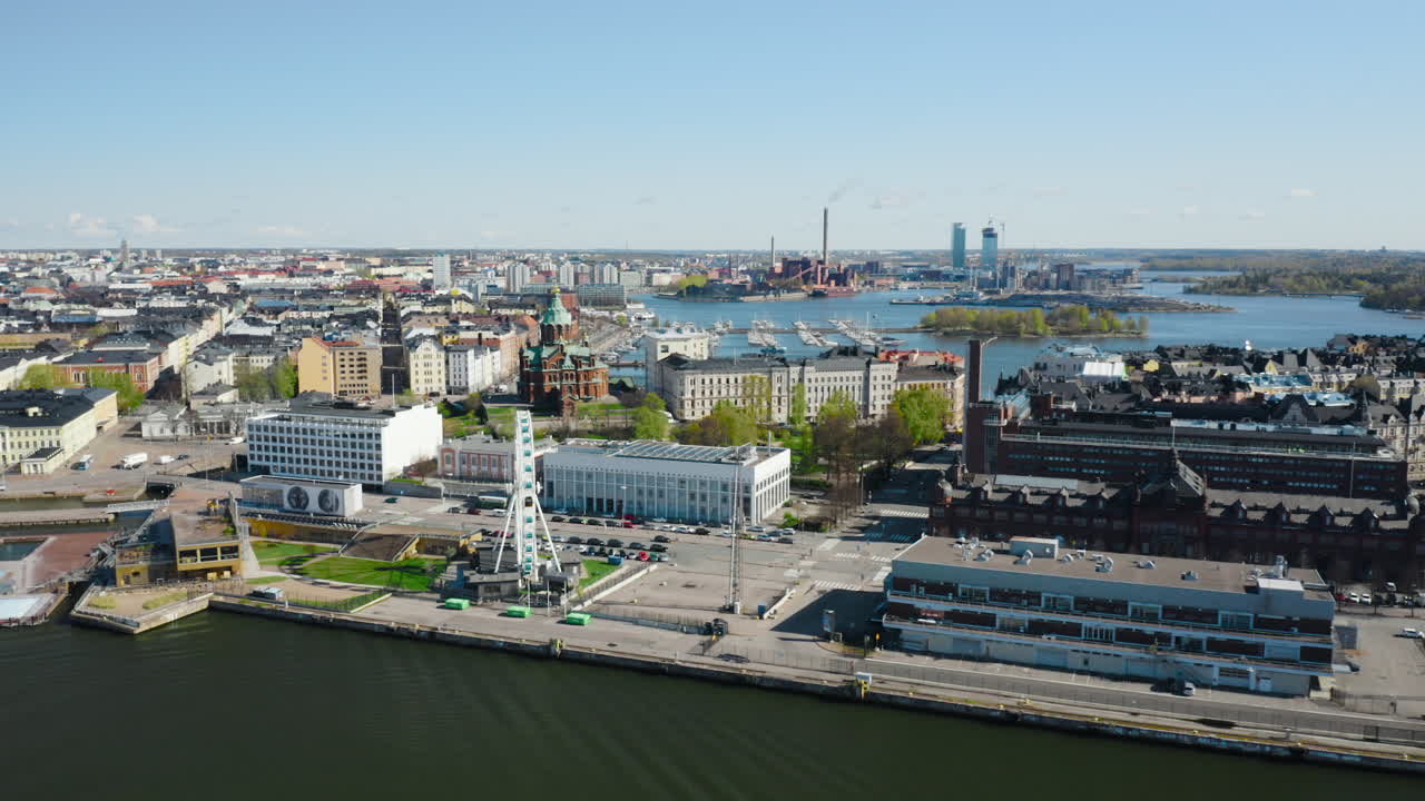 Aerial, tracking, drone shot Uspensky cathedral, the skywheel and buildings, in Katajanokka area, sunny, spring day, in Helsinki, Uusimaa, Finland
