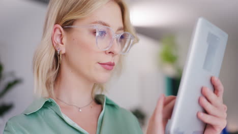 woman with glasses using digital tablet in office