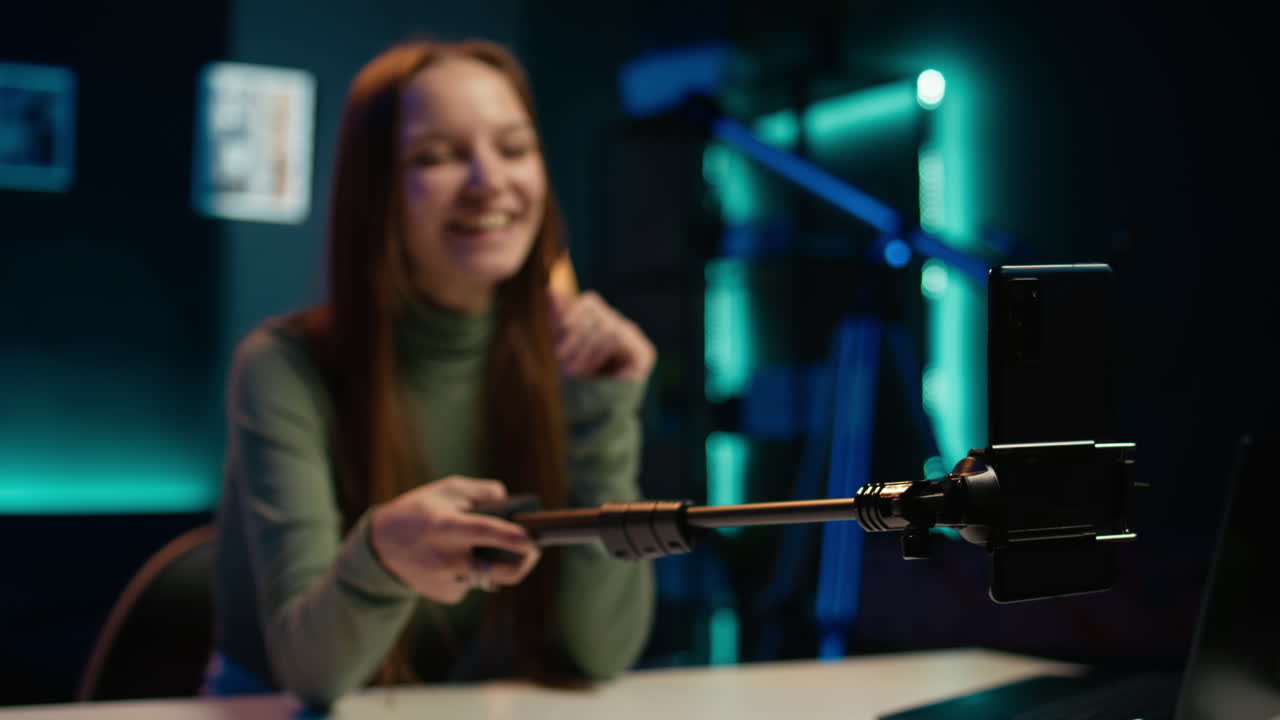 셀피 스틱에 있는 드폰의 클로즈업은 아파트에 있는 소녀가 vlog을 하기 위해 사용하는 것입니다.