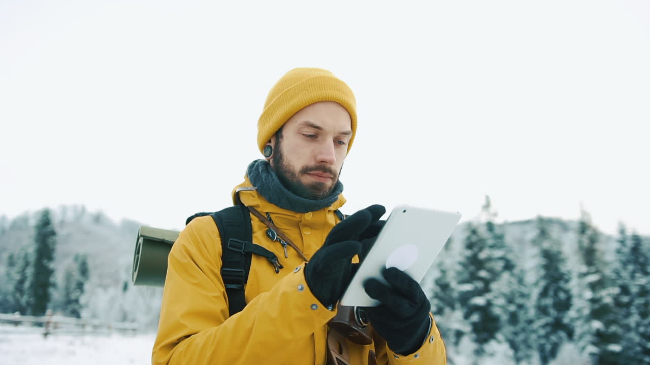 Uomo che usa un tablet in un paesaggio invernale innevato
