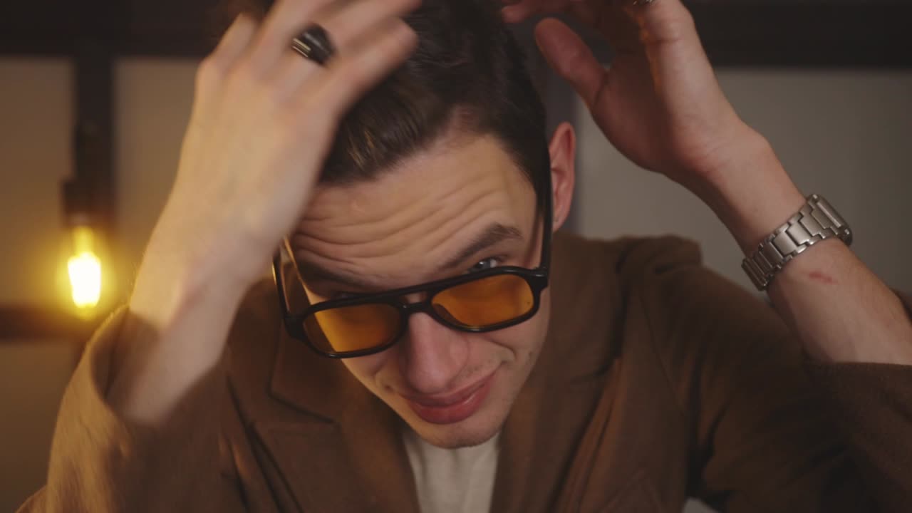 편광 선글라스를 쓴 쿨한 명랑한 남자는 떠나기 전에 머리를 고친다