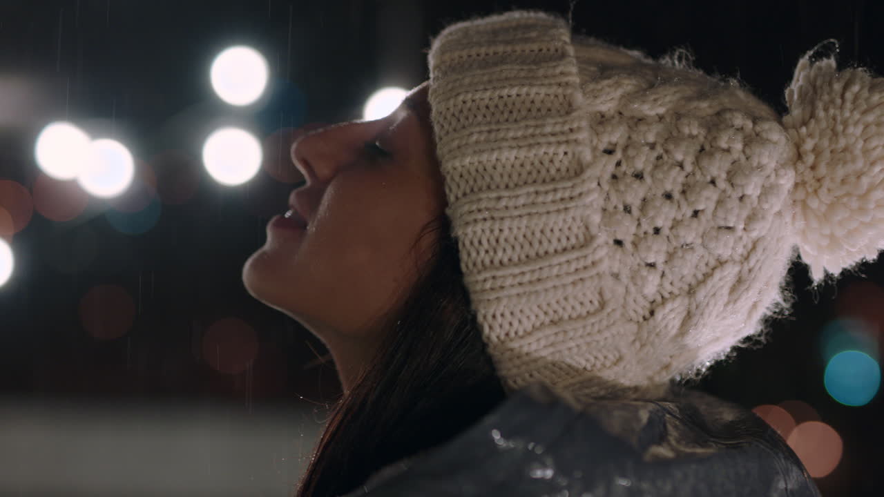 ⁇ 속에 서 있는 아름다운 젊은 여성이 부드러운 비방울이 피부를 만지는 것을 즐기고 있습니다.