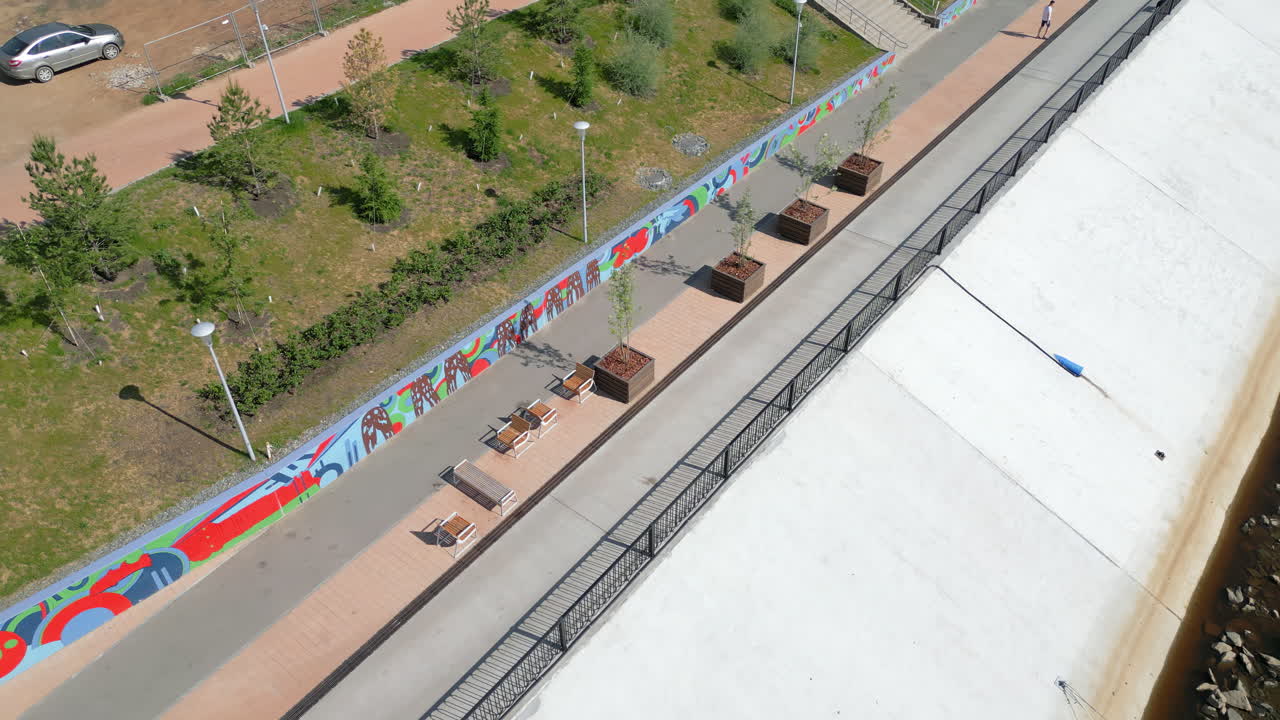 Aerial View of a Modern Riverside Embankment with Promenade and Mural