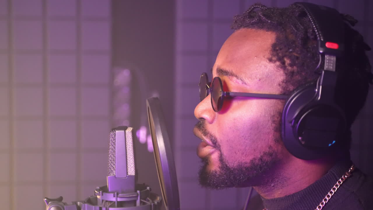 hombre cantando en un micrófono en un estudio de grabación