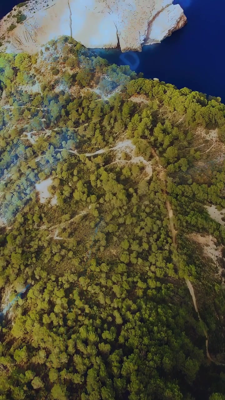 Video verticale: Drone che sorvola un promontorio, inclinando la telecamera per mostrare una scogliera, con un bagliore e un indicatore che salgono mappando.