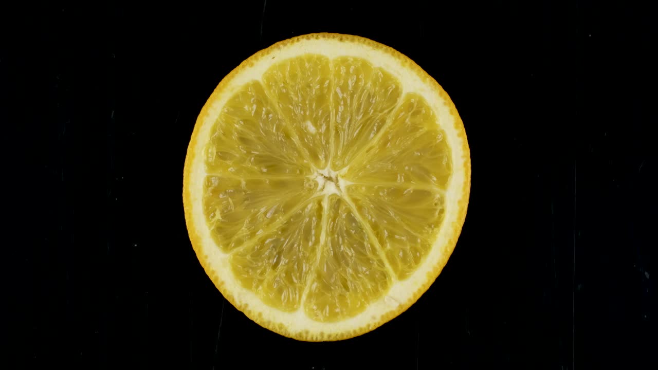 rotación de una rebanada de naranja sobre un fondo negro.