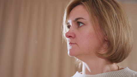 close up of thoughtful woman in soft sweater gently lifting head with calm expression while listening attentively during therapy session in warm indoor space with soft lighting and neutral curtains