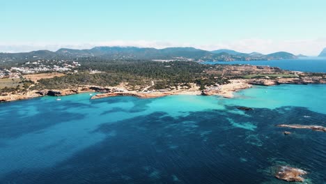 Aerial-view-of-the-beautiful-coastline-with-turquoise-blue-water-next-to-a-pine-forest