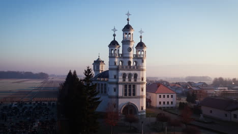 drone shot of a big church in a small village on flat lands in early morning hours, clear sky with no clouds