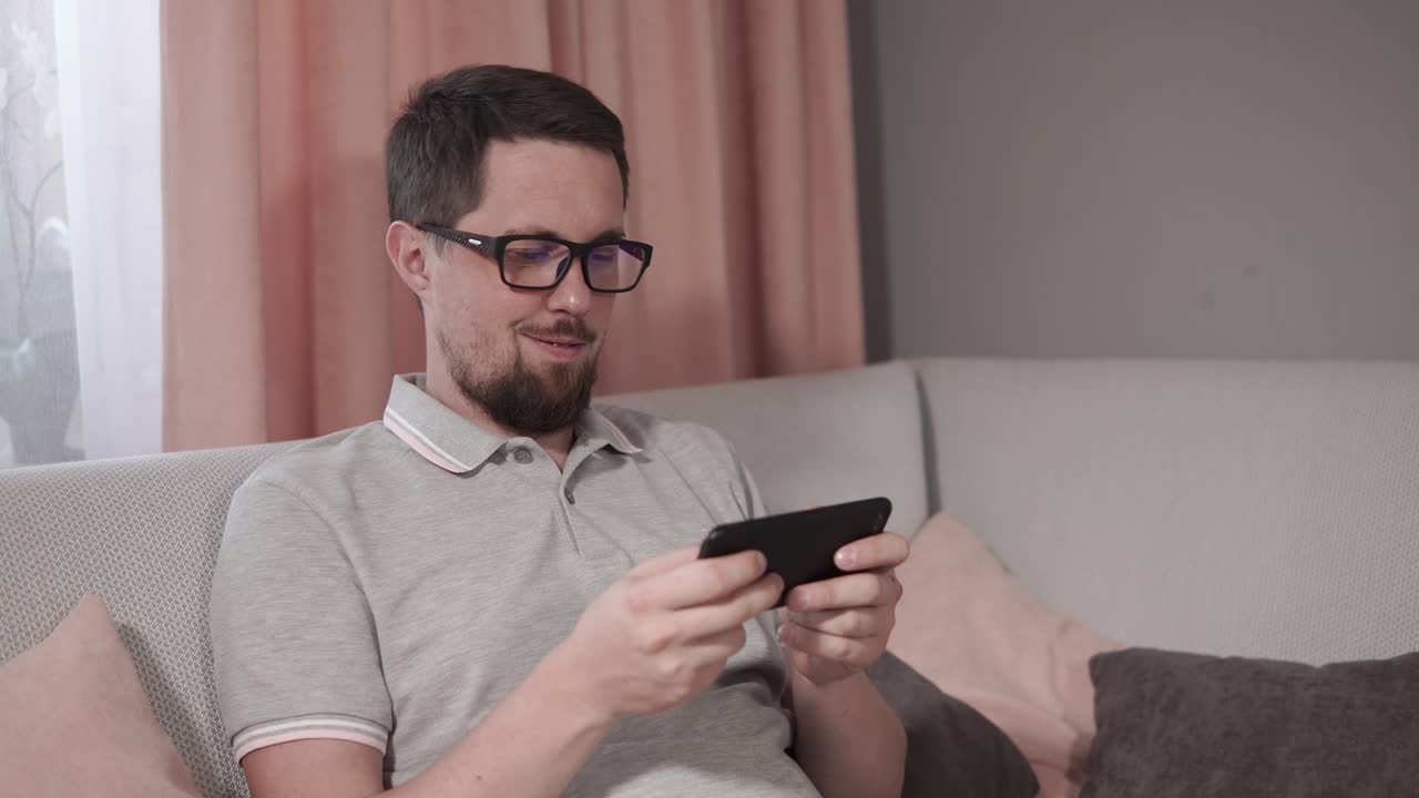 소파에서 스마트폰을 사용하는 남자