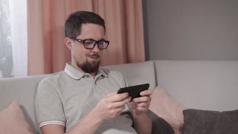 hombre usando un teléfono inteligente en un sofá