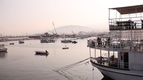 boat restaurant and cafe in a quaint harbor with mountains in the distance in coastal sea town of la mina in tripoli, northern lebanon