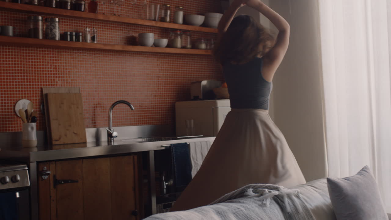 행복한 젊은 여성이 집에서 춤을 추고 즐겁게 여름 휴가를 축하하고 성공적인 라이프 스타일을 축하하기 위해 유쾌한 춤을 즐기고