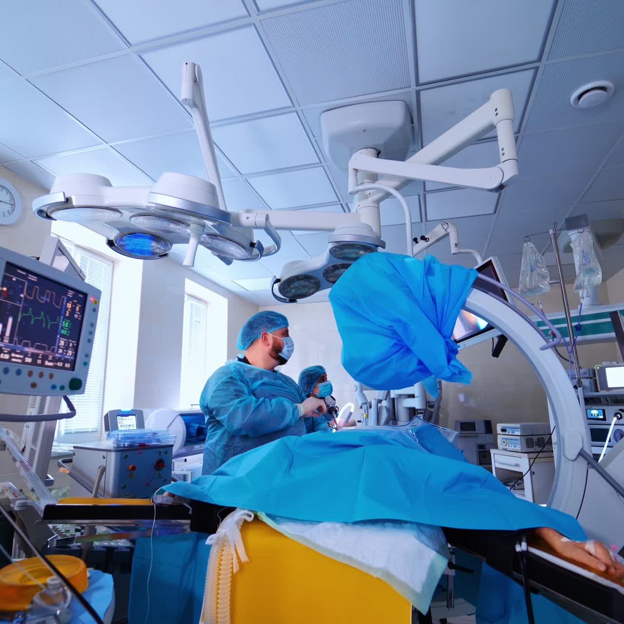 Contemporary equipment in the surgery room. Doctors in medical uniform doing an operation to a patient and using modern instruments in clinic.