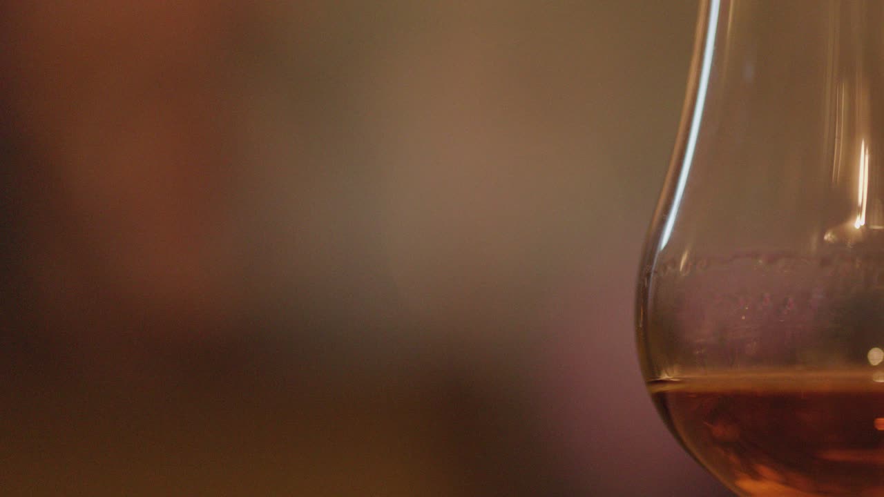 Close-up of whisky glass with amber liquid, warm bokeh background, evoking relaxed evening atmosphere