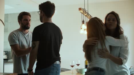 amigos sonrientes saludando y sentados a la mesa con vino y bocadillos