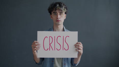 man holding a sign saying "crisis"